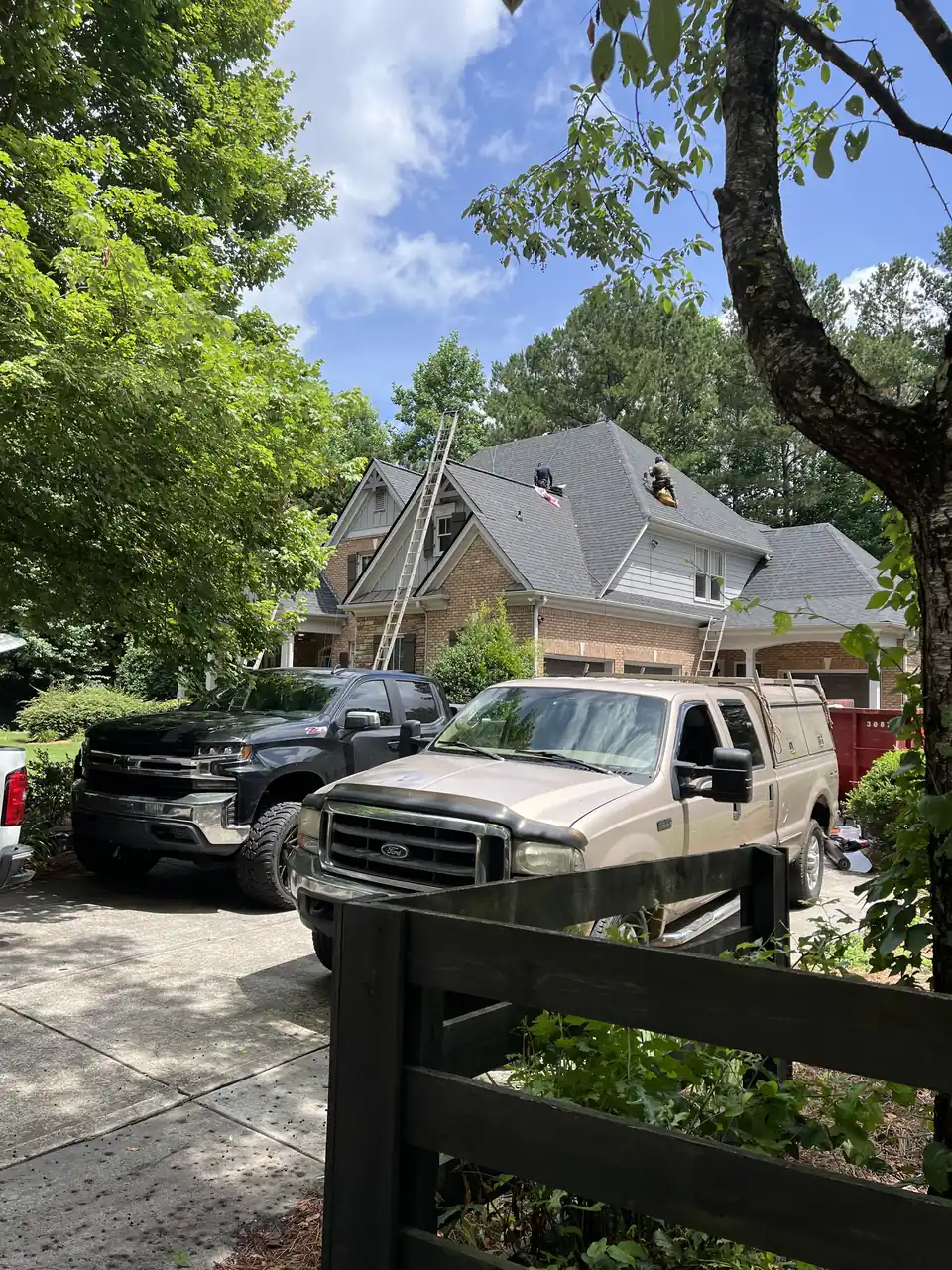 Atco Roofing work trucks parked at a residential job site