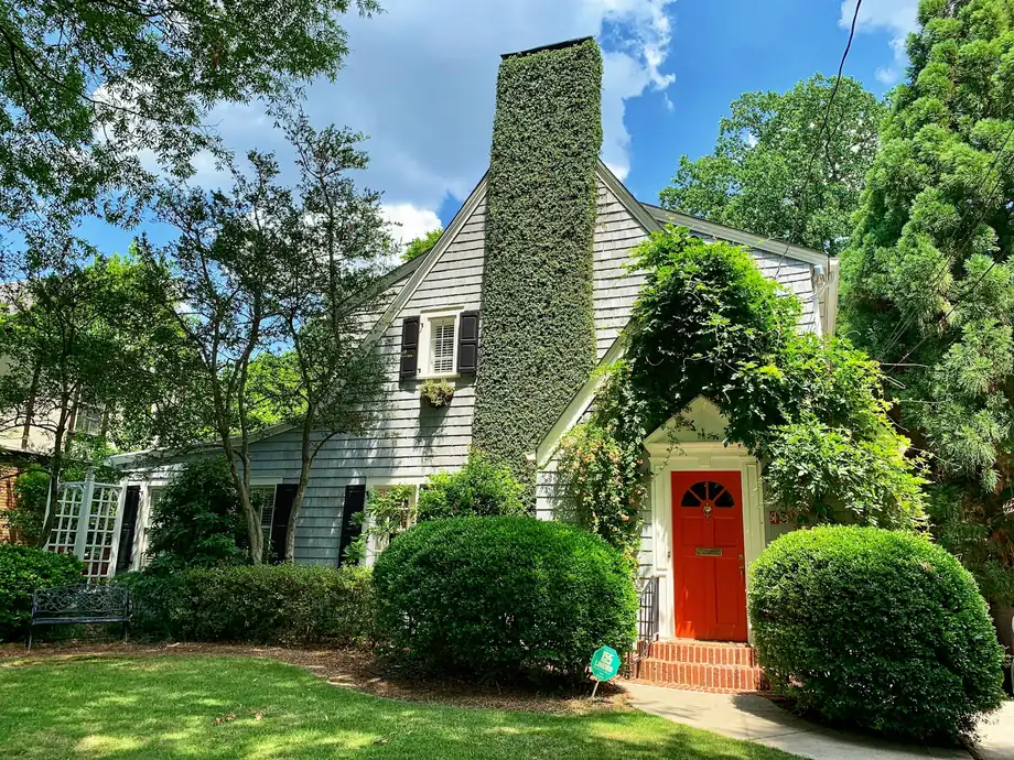 Cottage-style home with a red door and green landscaping