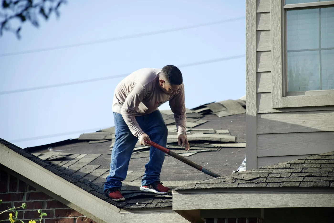 Roofer repairing damaged shingles on a residential roof